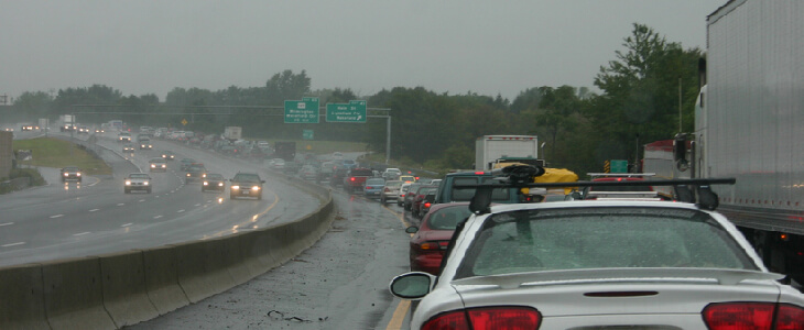 A rainy and wet highway road filled with traffic because of an accident