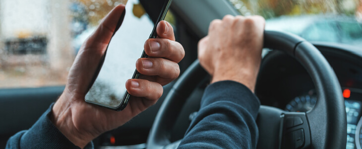 Man driving while looking at his phone